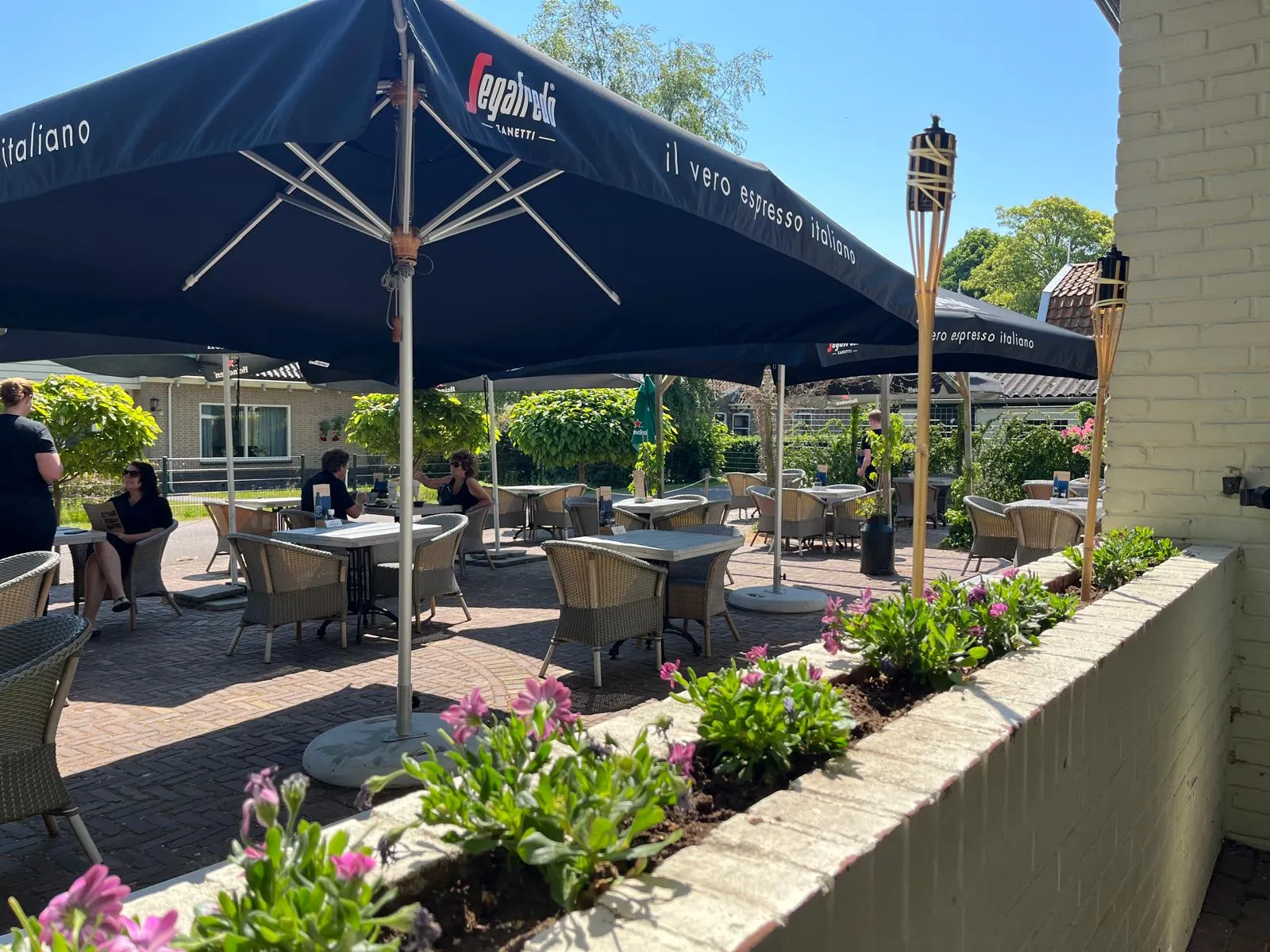 Het zonnige terras van Het Wapen van Middelie, met bloemen en parasols